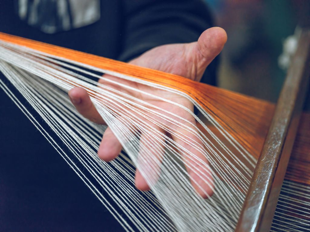 Una mano entrelazada con cuerdas de colores blancos y narajana
